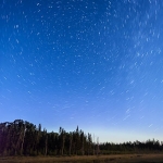 Stars over Mud Creek: The stars circle around the north star over Mud Creek. A slight glow of northern lights on the horizon. Minnesota.