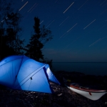Expedition Campsite: Star trails stream by above a kayaking campsite on Lake Superior's shoreline. Lake Superior Water Trail, Minnesota.