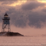 Winter Lake Superior Sunrise: The clouds turn purple and pink during a winter sunrise over the Grand Marais lighthouse. Lake Superior, Minnesota.