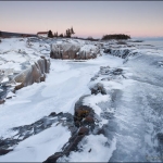 Winter on Artist's Point: Rocks on Artist's Point covered in ice. The Coast Guard building in the background.