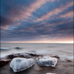 Quorum of Three: At sunset, Lake Superior waves roll over a rock protecting ice-coated boulders. Colvill, Minnesota. (110222-60)