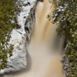The lowest falls on the Cascade River in the spring. A light snow covers the shoreline.