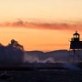 Grand Marais Lighthouse and breakwall with waves crashing over.