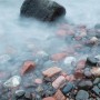 A wave washes over a rock beach.