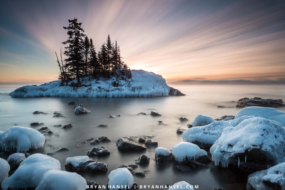 The clouds above the tombolo on Lake Superior look like rays spreading across the sky. Winter, Cook County, Minnesota.