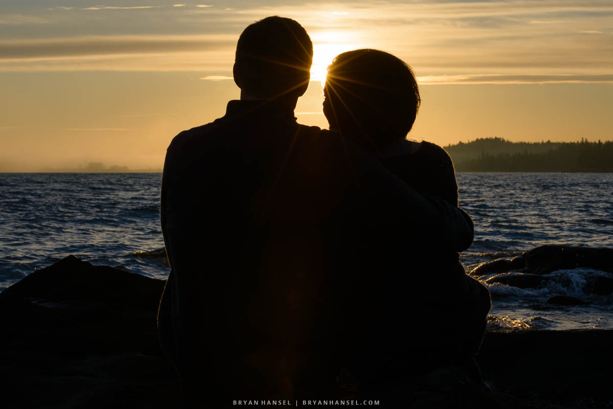 a portrait of a couple at sunset with Grand Marais in the background.