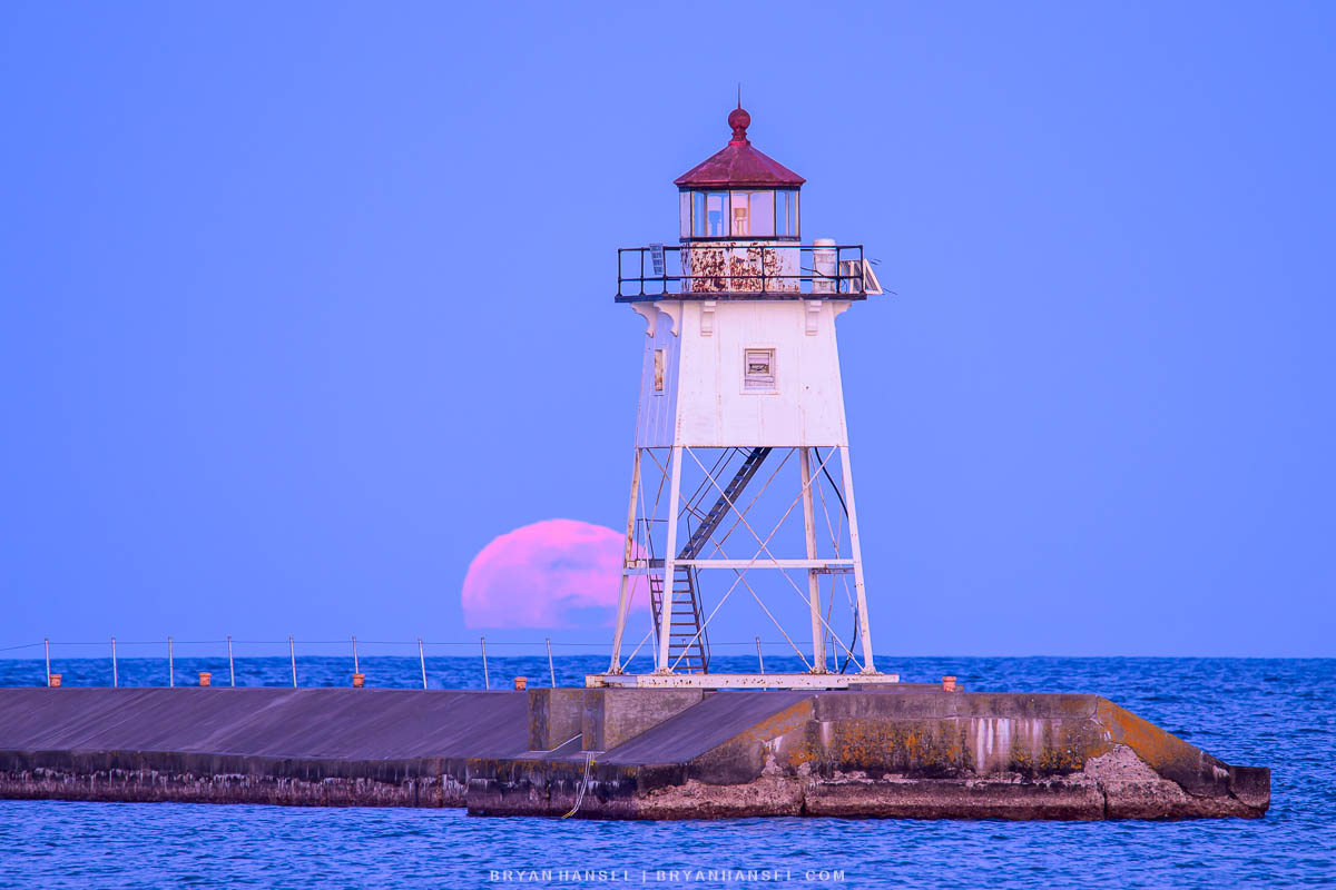 the full moon rising over the Grand Marais lighthouse taken during a photo workshop