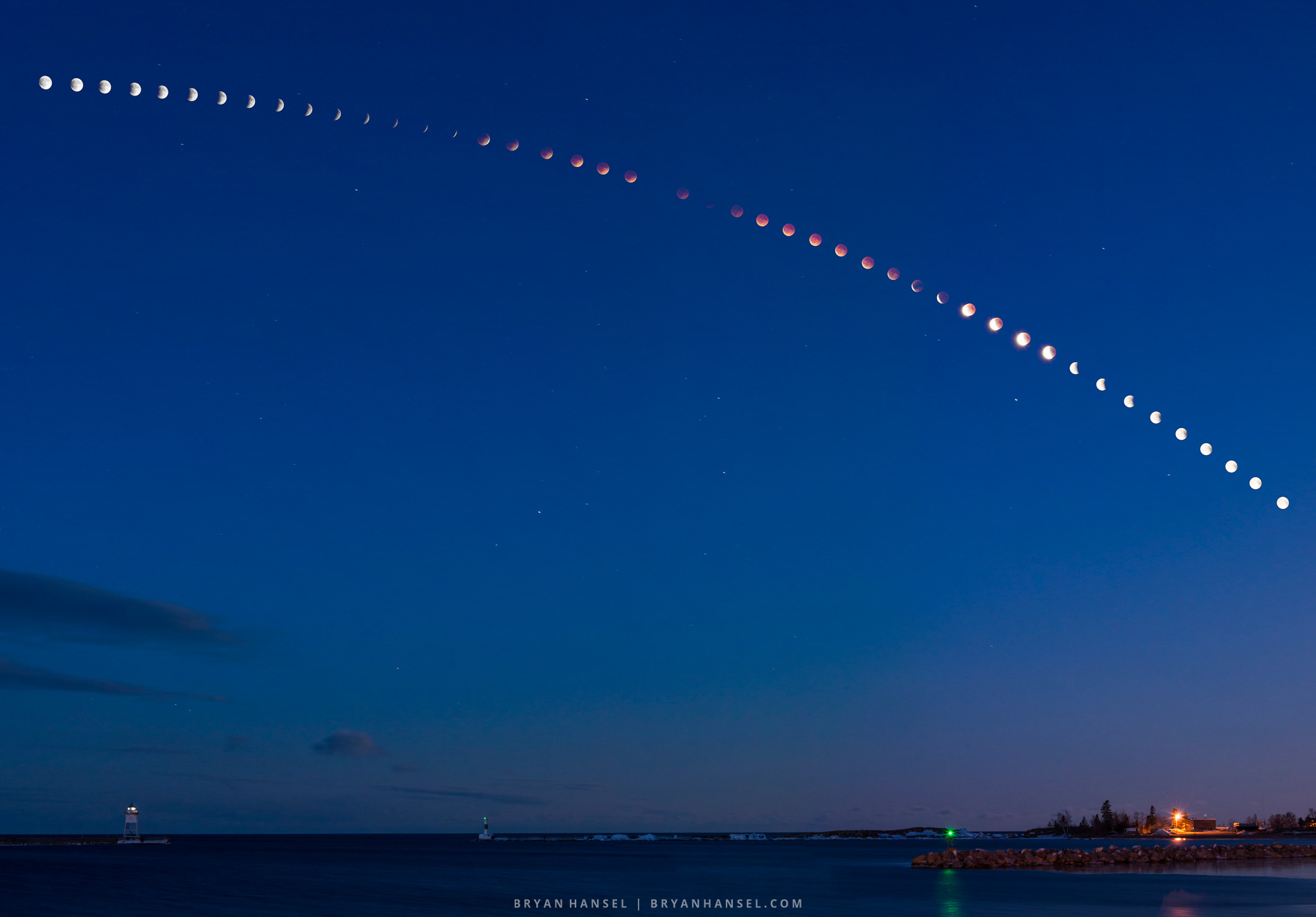 Composite image showing the full arc of the April 2014 blood moon lunar eclipse over the Grand Marais harbor on Lake Superior, from full moon through totality and back, with the lighthouse visible at lower left.