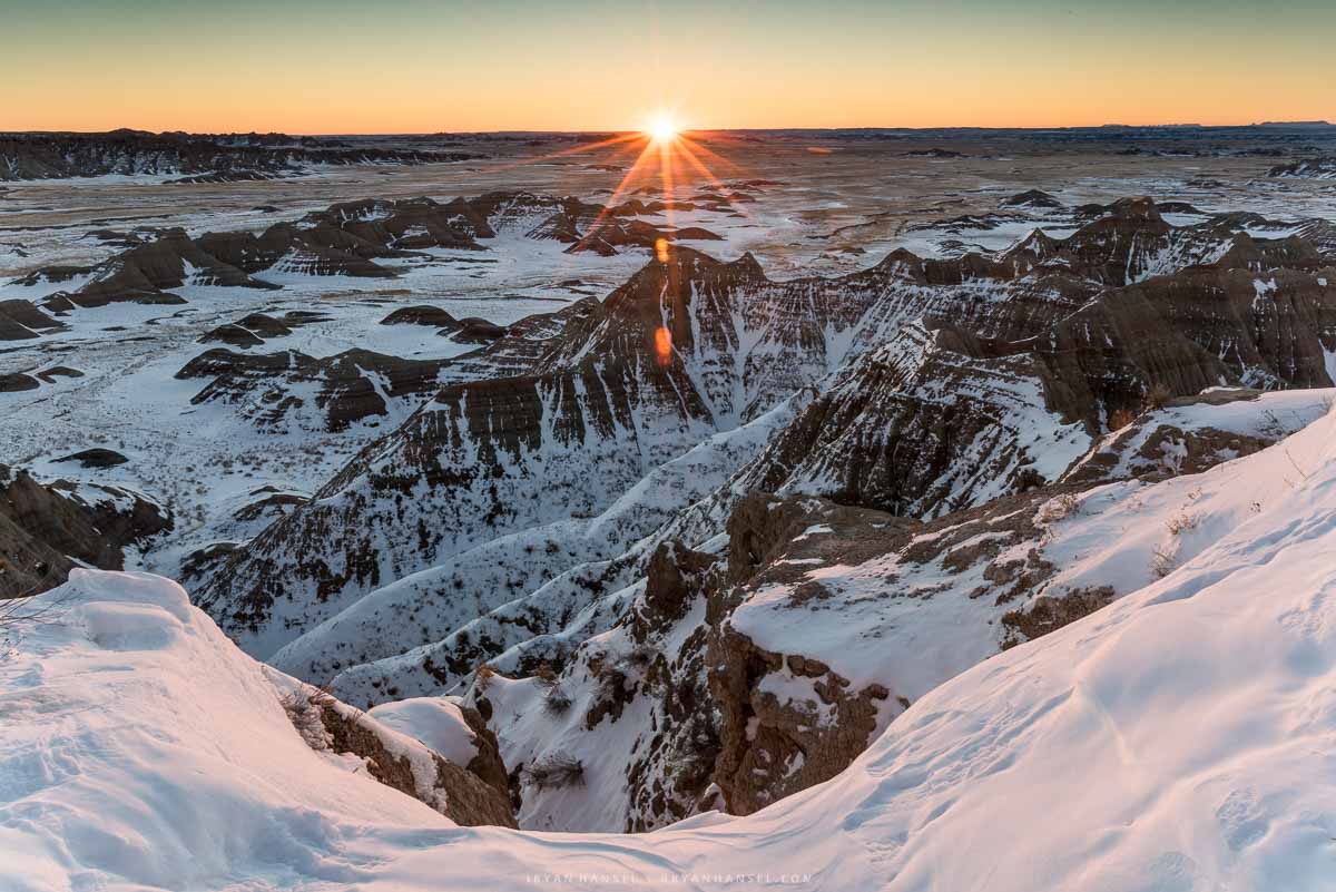 the sun rising over Big Badlands Overlook and the overlook is covered in snow